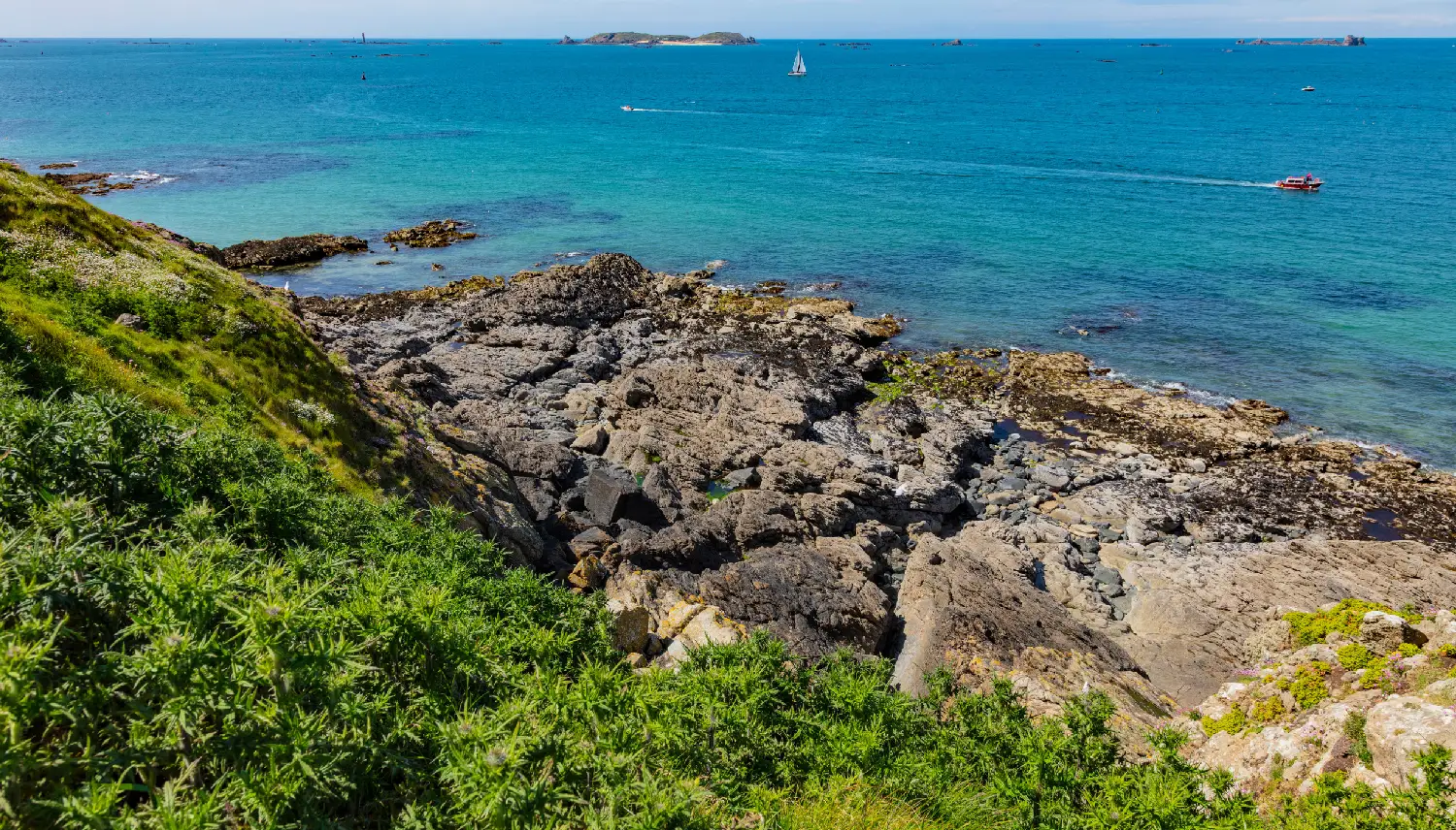 beautiful view from the island towards the sea, small islets and a green slope, Saint Malo, France